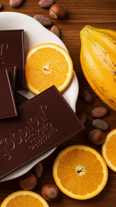 Goodnow Farms chocolate bars on a white plate with cocoa beans on a wooden surface
