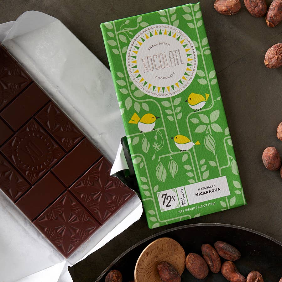 Green chocolate bar packaging with cocoa beans on a brown surface